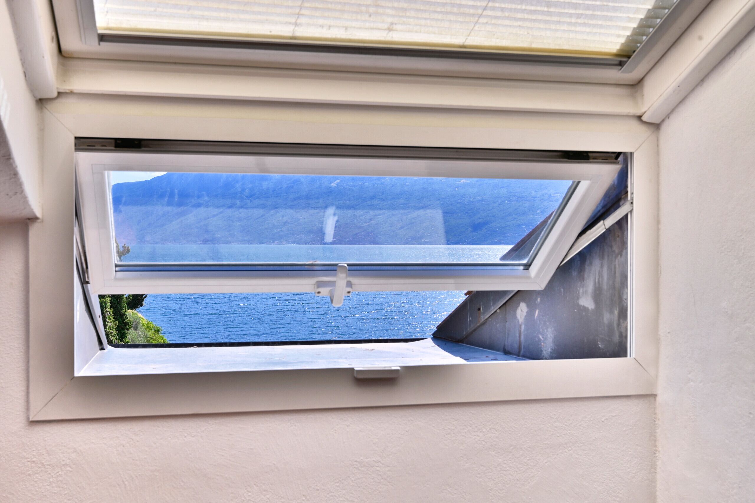 A skylight window with a view of a body of water and a mountain.