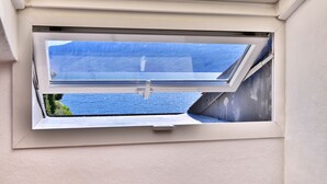 A skylight window with a view of a body of water and a mountain.