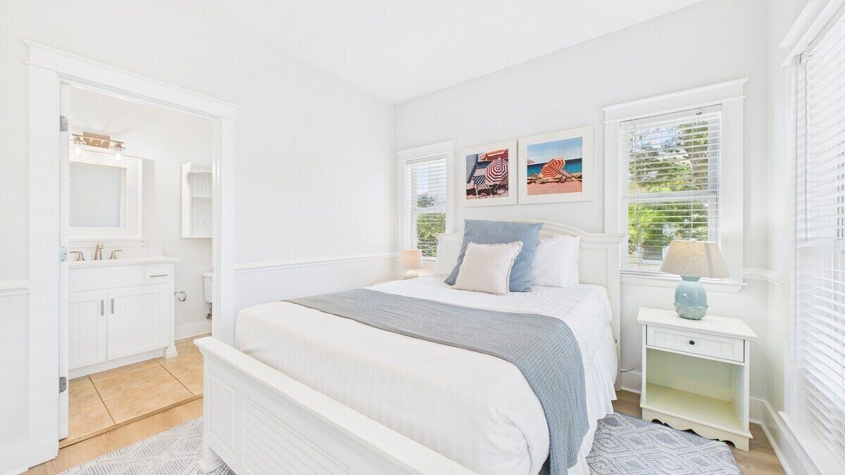 A bedroom with a bed, nightstands, a dresser, and a window with blinds.