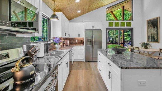 A modern kitchen with white cabinets, a marble countertop, and a stainless steel refrigerator. - Forest Haven 1030-Luxe Cabin-Sleeps 7 (Kingston Springs)