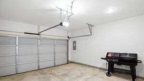 A garage with a concrete floor, a white garage door, and a black barbecue grill. - New modern Townhouse, 3BR, 2.5B, near Mid City (Huntsville)