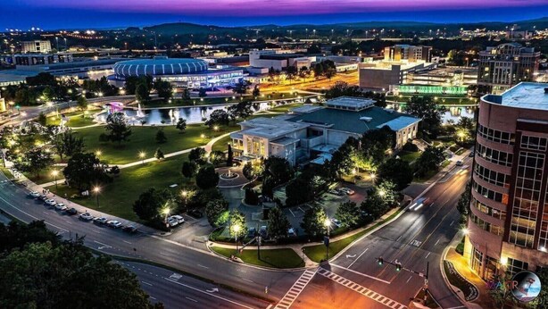 A cityscape at dusk with a stadium, parking areas, and modern buildings. - New modern Townhouse, 3BR, 2.5B, near Mid City (Huntsville)