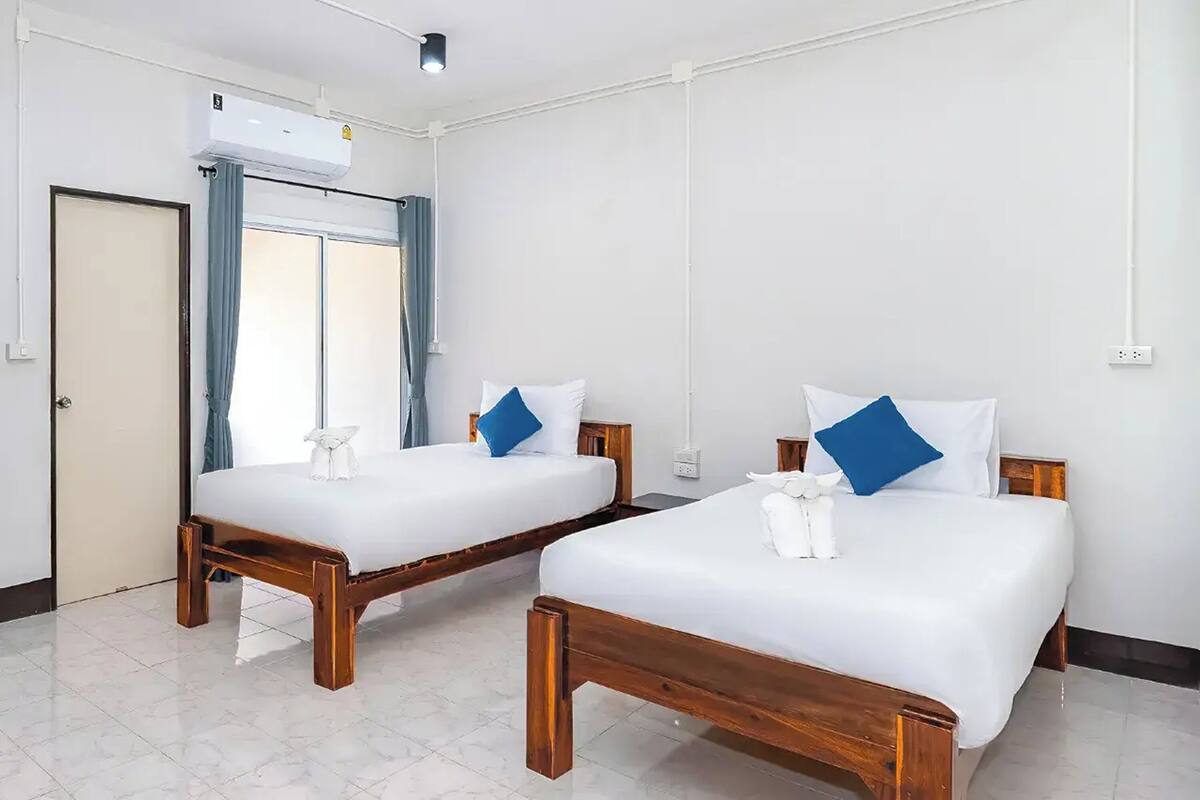 Ein Hotelzimmer mit zwei Holzbett, weißer Bettwäsche und einem Fenster mit Vorhängen.