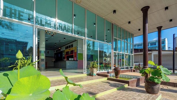 A hotel entrance with large glass windows, a tiled patio area, and potted plants. - The Palm Krabi Residence And Resort  (Krabi)