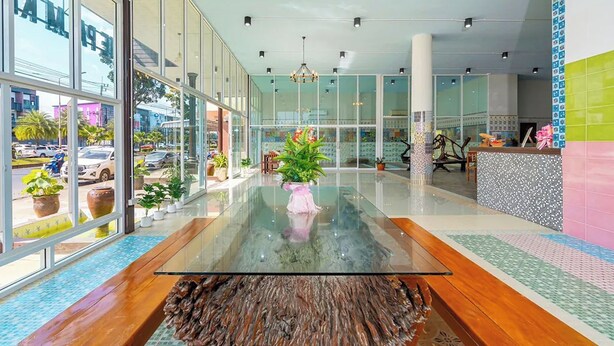 Un moderno vestíbulo de hotel con una mesa de centro de vidrio, plantas en macetas y un mostrador de recepción.