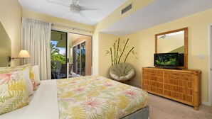 A bedroom with a bed, a television on a wooden cabinet, a chair, and a large window with curtains. - Big Island Vista Waikoloa B203 2 Bedroom Condo (Waikoloa)