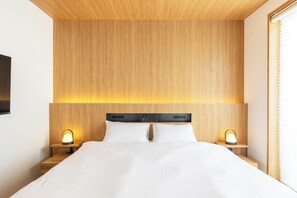 A modern hotel room with a wooden headboard, two bedside tables with lamps, and a large bed with white linens. - Dash Living Gojo (Kyoto)