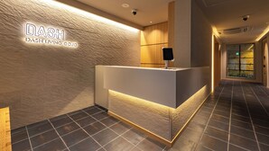 Een receptiebalie met een gestructureerde wand en een bord waarop 'DASH DASH LIVING CO., LTD.' staat.