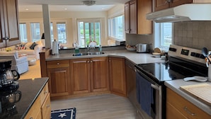 A modern kitchen with wooden cabinets, a black stove, and a large window providing natural light. - 4BR Oceanview Academic Rental in Stonington CT 09/01 thru 05/31 (Stonington)