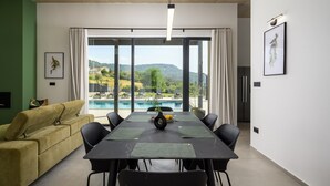 Un comedor moderno con vista a la piscina, un sofá y obras de arte en las paredes.