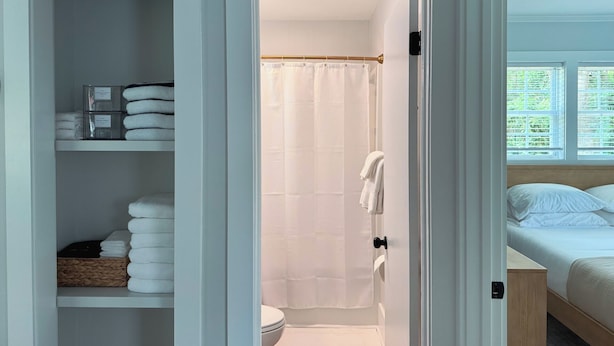 Ein Badezimmer mit Duschvorhang, Toilette und einem Bett mit Holz Kopfteil.