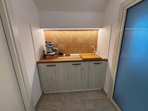 Une cuisine compacte dotée d’un plan de travail en bois, de placards intégrés et d’un crédence décorée.