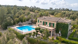 Una villa con piscina, rodeada de exuberante vegetación y árboles.