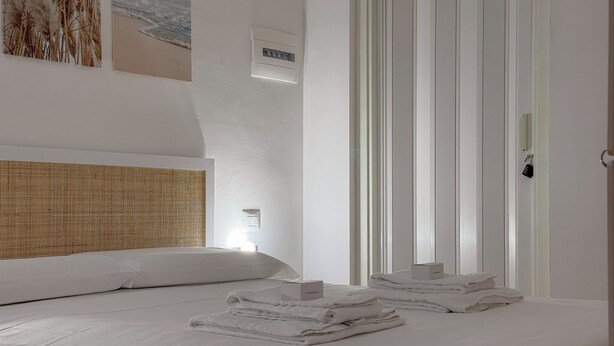 Een hotelkamer met een bed, nachtkastje, een wandlamp en een deur met slot.