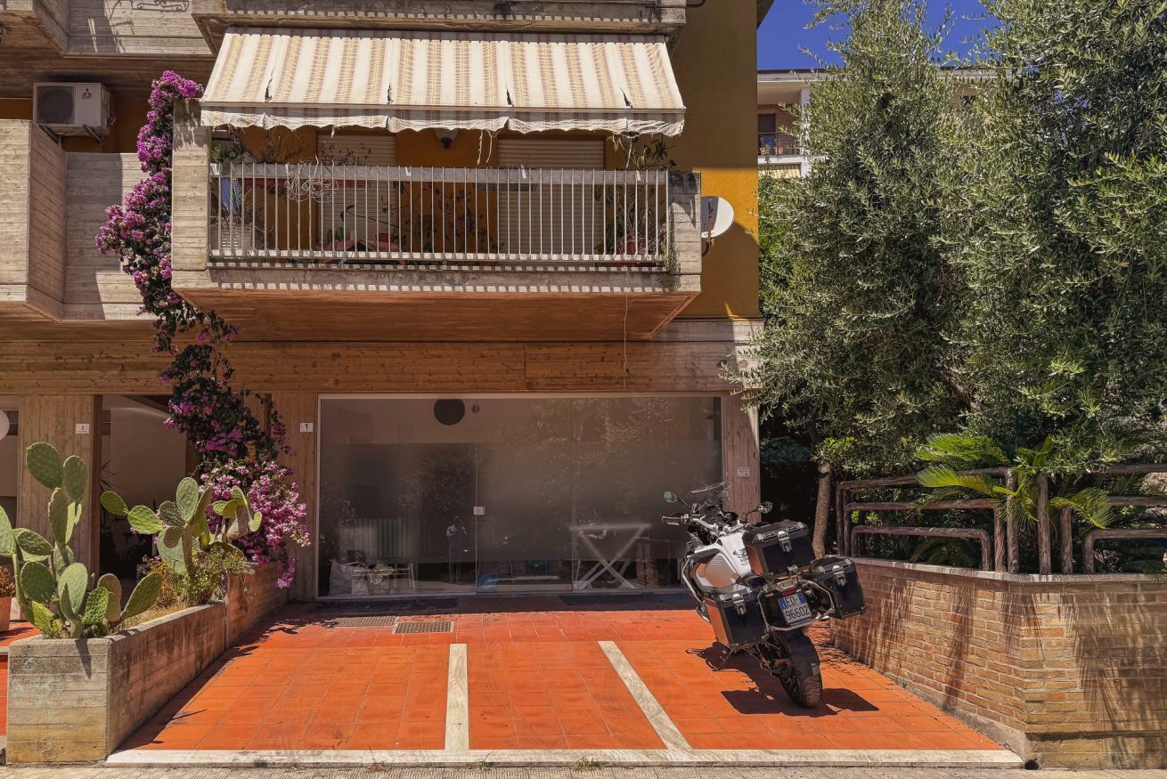 A building with a balcony, a motorcycle parked in front, and a red-tiled entrance.