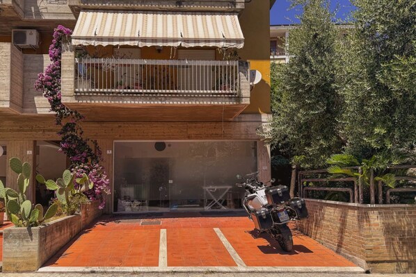 Un edificio con un balcón, una motocicleta estacionada frente a él y una entrada con tejas rojas.