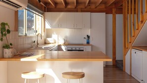 A modern kitchen with wooden beams, white cabinets, and a central island with stools.