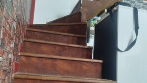 A wooden staircase with a red brick wall on one side and a white wall on the other.