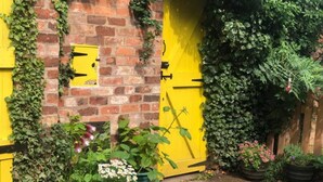 A brick wall with a yellow door, potted plants, and a small window. - Leaf Retreat - A Rest in Nature. Pet-friendly! (Louth)