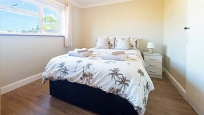 Une chambre à coucher avec un lit, une table de chevet, une fenêtre et une porte.