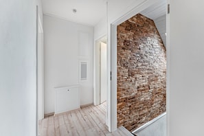 Ein Flur mit einer weißen Tür, einem Heizkörper und einer Wand mit Ziegelmuster.
