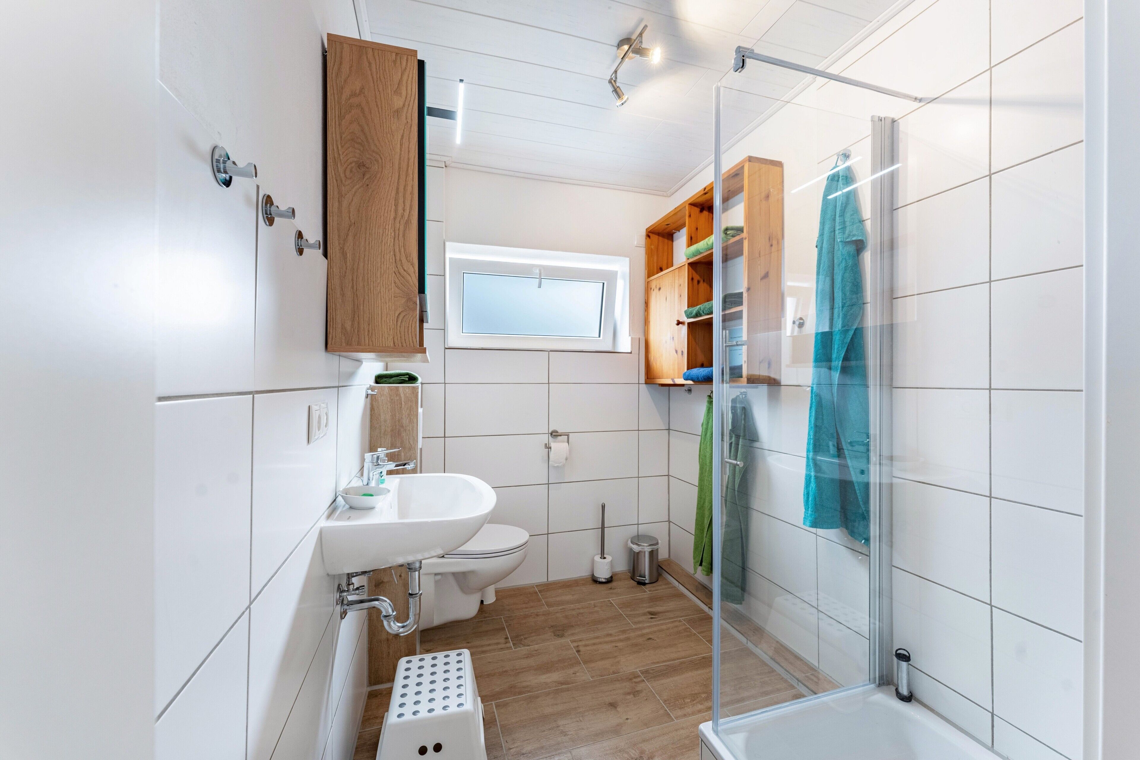 Ein Badezimmer mit Waschbecken, Toilette, Dusche und einem Fenster.