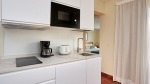 Cocina compacta equipada con microondas, cafetera y tostadora.