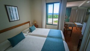 Une chambre d’hôtel avec deux lits, un bureau et une vue sur l’extérieur.