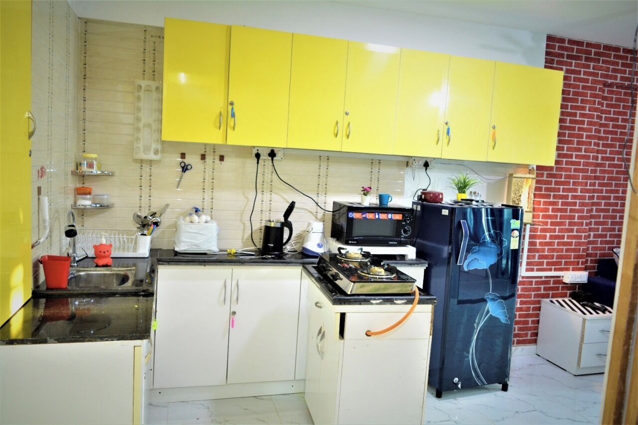 A compact kitchen with yellow cabinets, a black refrigerator, a microwave, and a gas stove.