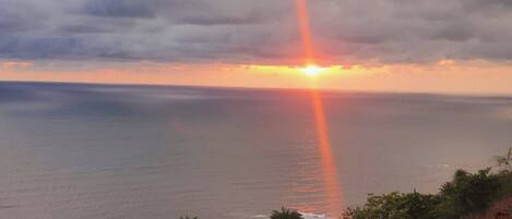 A sunset over the ocean with a visible rainbow.