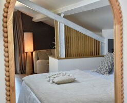 Un dormitorio con cama, mesita de noche, lámpara, ventana con persianas y cabecero de madera.