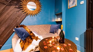 A cozy room with a tufted sofa, a round wooden coffee table with candles, and a mirror on the wall.