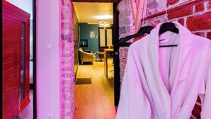 A hallway with a red door, a brick wall, and a robe hanging on a rack.
