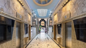 A hallway with a checkered floor, stone walls, and two elevators. - Complete Studio in Curitiba Eda0001 (Curitiba)