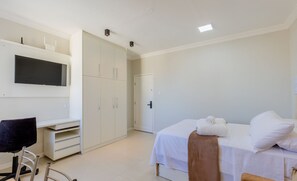 A bedroom with a bed, a desk, and a chair.