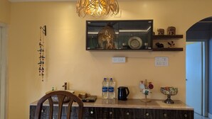A kitchen with a marble countertop, a wooden chair, a hanging light fixture, a mirror, and decorative items on shelves. - Seneh Homes - An Assamese homestay experience with WiFi, Views, & AC in Guwahati (Guwahati)
