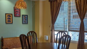 A dining area with a round table, four chairs, a ceiling fan, and two hanging lamps. - Seneh Homes - An Assamese homestay experience with WiFi, Views, & AC in Guwahati (Guwahati)