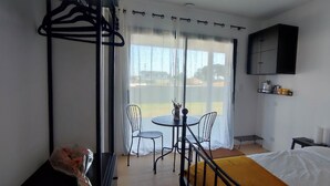 Une chambre d’hôtel avec un lit, une petite table avec des chaises, une fenêtre avec des rideaux, un placard noir et une carte accrochée au mur.