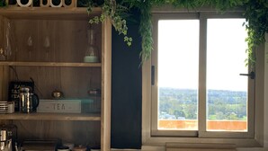 Eine Küche mit Holzregal, einer Kaffeemaschine, einer Teeausstattung und zwei Barhocker.