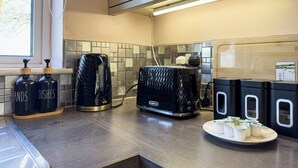 Une cuisine équipée d’une machine à café, d’un grille-pain et de briques de lait posées sur le plan de travail.