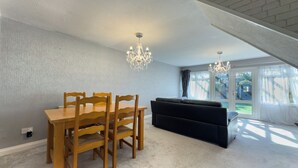 Un coin repas avec une table et des chaises en bois, un canapé noir et un lustre.