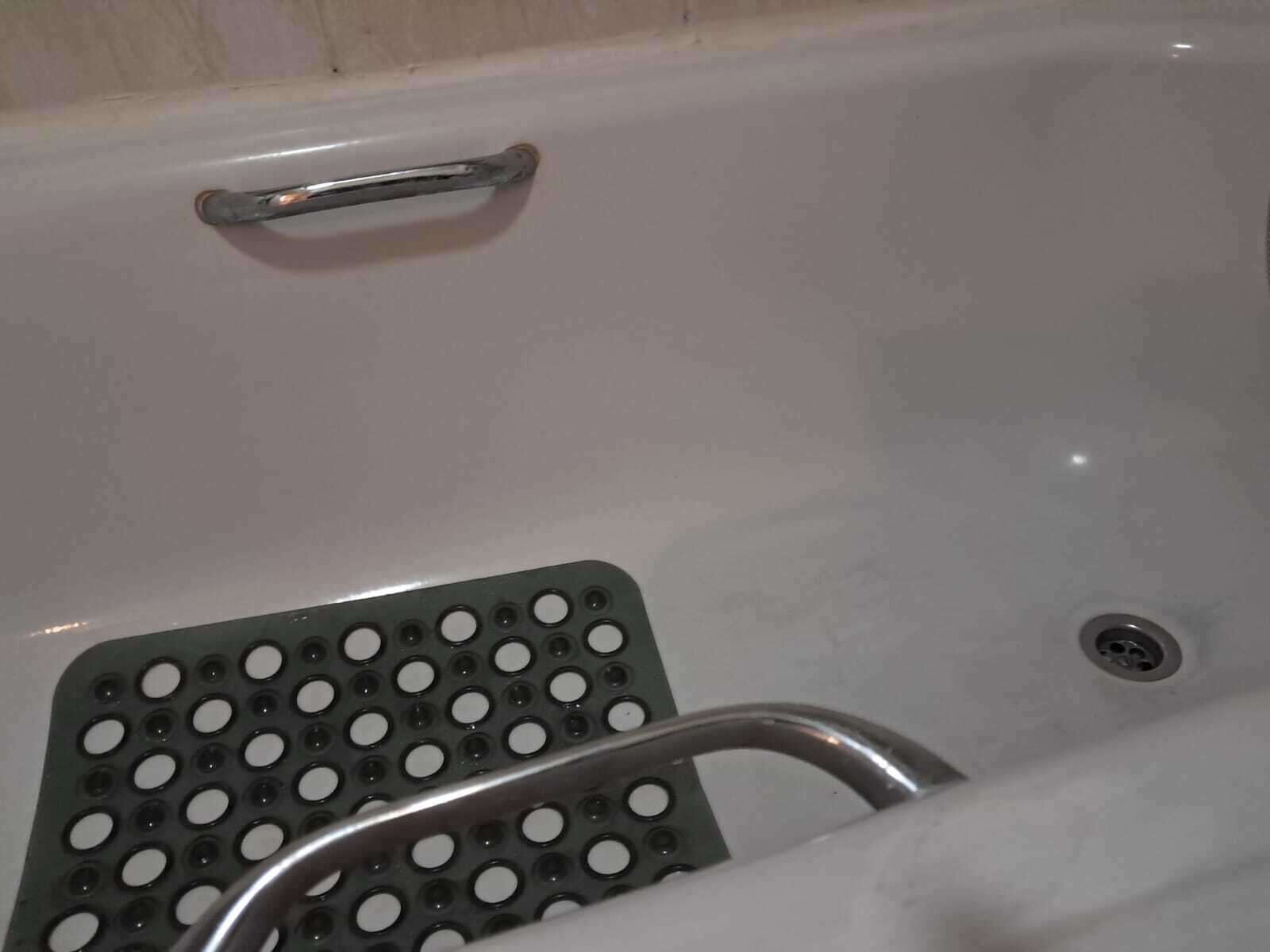 Una bañera con asiento integrado para la ducha y desagüe.