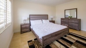 Un dormitorio con cama, mesitas de noche, cómoda y espejo.