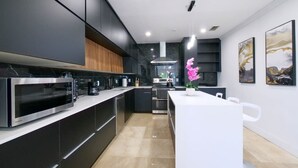 Una cocina moderna con armarios oscuros, encimera blanca y una isla central.