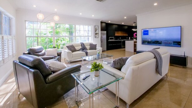 Una sala de estar moderna con una mesa de centro de vidrio, dos sofás y un televisor de pantalla plana montado en la pared.