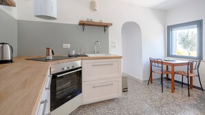 Una cocina moderna con horno empotrado, un lavamanos y una zona de comedor con mesa y sillas.