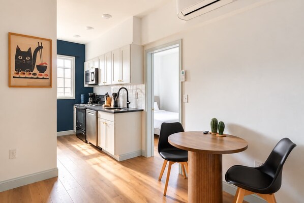 A modern kitchen with white cabinets, a black countertop, and a dining area with a round wooden table and black chairs.