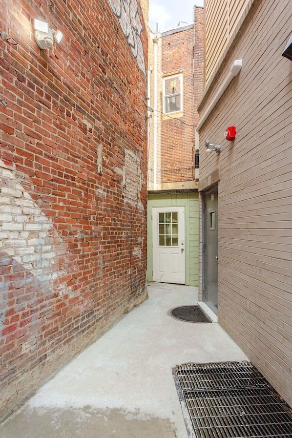 A narrow alleyway with a brick wall on one side and a wooden door on the other.