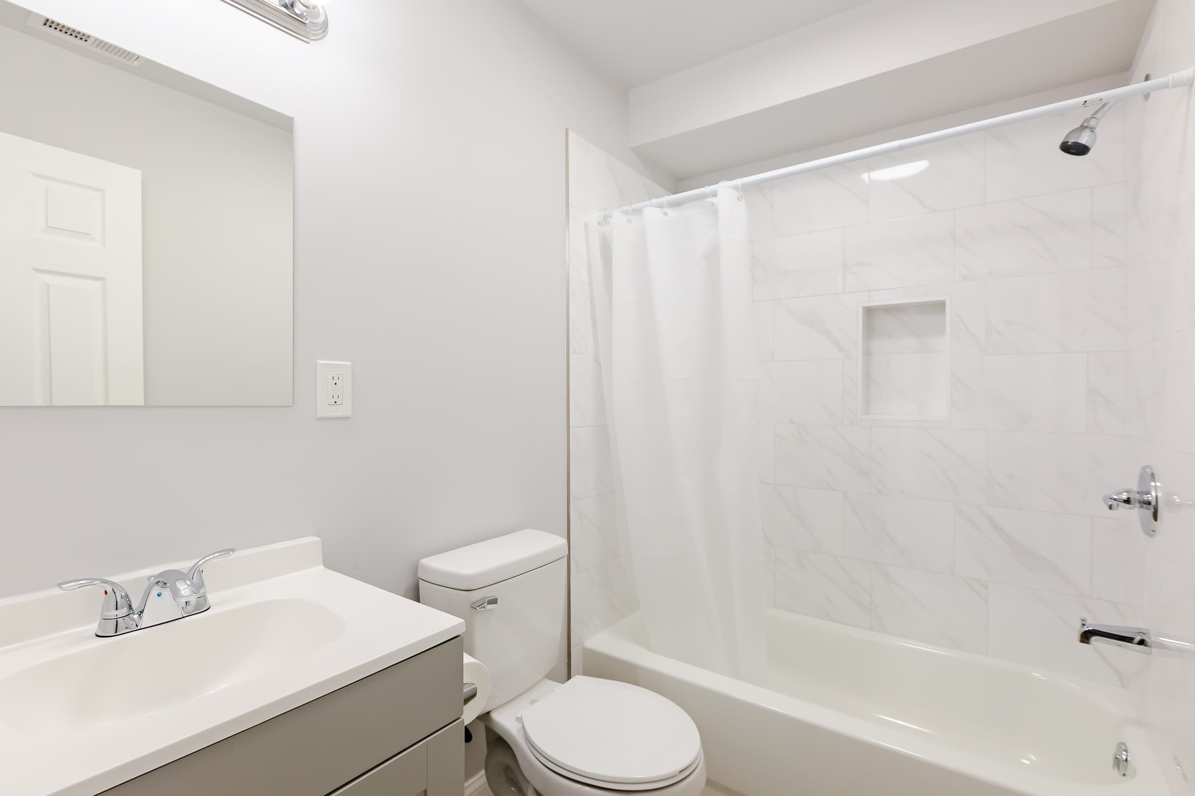 A modern bathroom with a white sink, toilet, and bathtub.