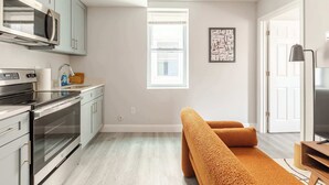 Eine moderne Küche mit Edelstahlgeräten, einem Fenster und einer gemütlichen Sitzecke mit einem komfortablen, orangefarbenen Sofa.
